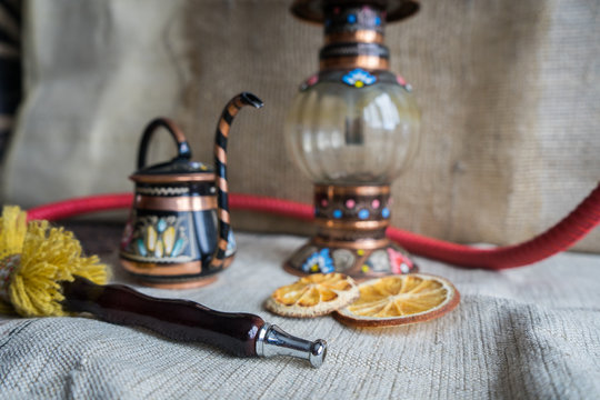 .Oriental theme still life with hookah mouthpiece, teapot and dried orange. Beautifully painted hookah on the tablecloth