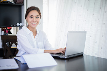 beautiful Asian business women checking document and using notebook and smiling happy for working