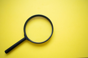 Magnifying glass isolated on bright yellow background, bottom left corner