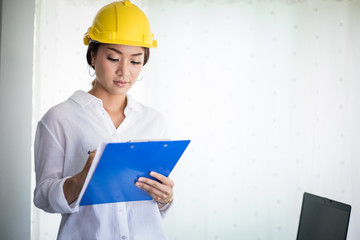  Asian women engineering inspecting and working and holding blueprints at office