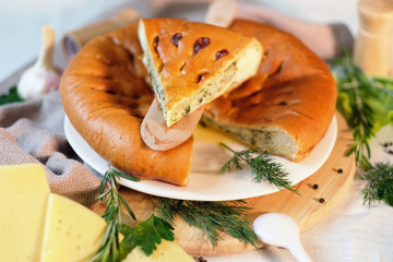 Round closed homemade baked pie with cheese and parsley
