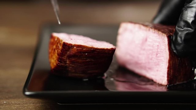 Chef cuts a filet mignon steak and shows it in a cut.
