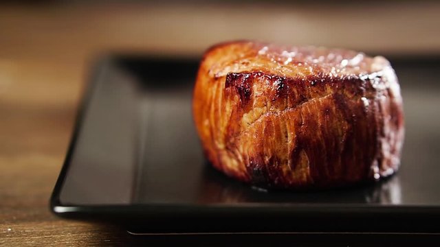 Chef's hand puts filet mignon steak on a plate.