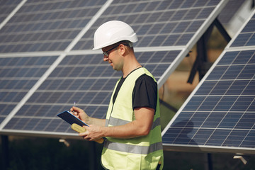 Engineer in a white helmet. Man near solar panel. Worker with a folder.