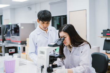 Two  medical  scientist working in Medical laboratory , young female scientist looking at microscope
