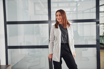 Portrait of young woman in white formal clothes that standing indoors