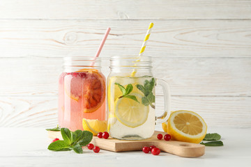 Glass jars with lemonade on wooden background. Fresh drink