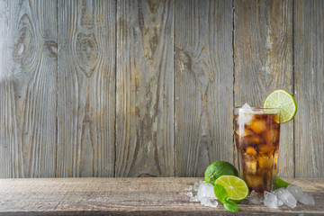 Summer iced alcohol drink with cola and lime. Rum and cola Cuba Libre cocktail. One long glass on...