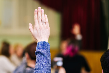 a man raises his right hand in a meeting. Voting