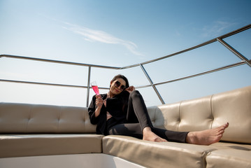 Luxury asian woman in black suit drinking champagne on the yacht.