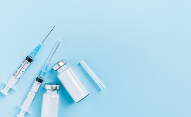 two syringes and two ampoules with medicine without a label on a blue background the concept of a coronavirus vaccine