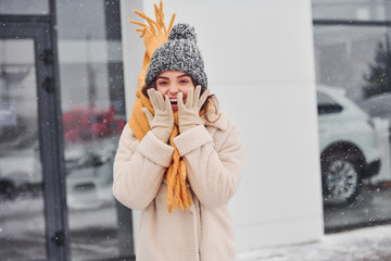 Fototapeta premium Cheerful young girl smiling standing and smiling outdoors. Snow is falling