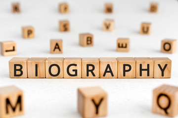 Biography - word from wooden blocks with letters, the life story biography concept, random letters around white background