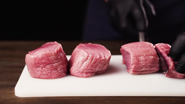 Chef cuts a tenderloin to prepare a filet mignon steak.