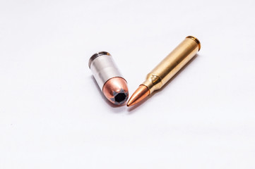 Two bullets, a 45 auto hollow point and a 223 caliber rifle bullet on a white background