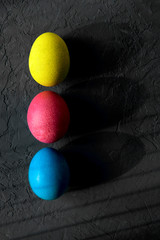 Colored easter eggs with deep shadows on a black background, top view.Easter concept