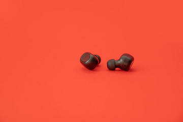 Wireless black headphones on a red background. Modern future technology concept