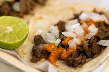 Taco mexicano de bisteck en tortilla de harina con cebolla y salsa roja.