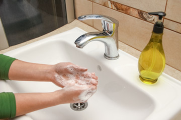 A Washing hands with soap under the faucet with water
