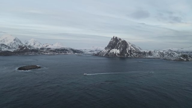 Fishing boat sailing to the ocean in arctic area of Lofoten Islands located north of norway during winter.Winter is main fishing season and cod fish is very famous from Norway.Mountains in background