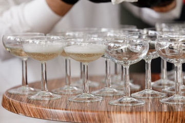 sparkling wine, champagne in glasses on the wooden table. waiter in black gloves pours alcohol into glasses in the restaurant. selective focus