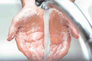 Soapy hands at sink with running water