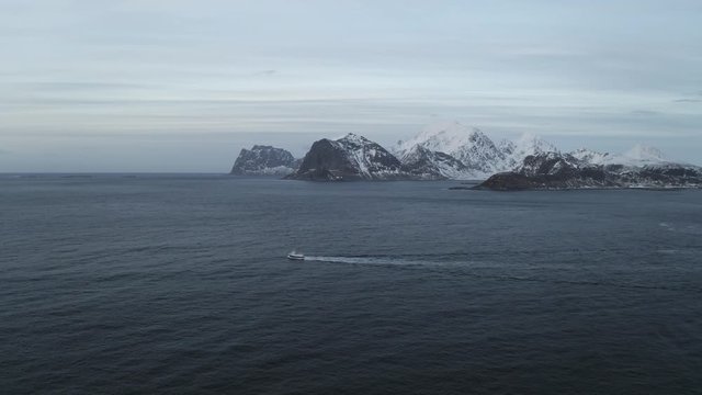 Fishing boat sailing to the ocean in arctic area of Lofoten Islands located north of norway during winter.Winter is main fishing season and cod fish is very famous from Norway.Mountains in background