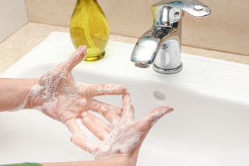 A Washing hands with soap under the faucet with water