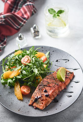 Hot smoked salmon with arugula salad, cherry tomato and orange. Healthy eating.