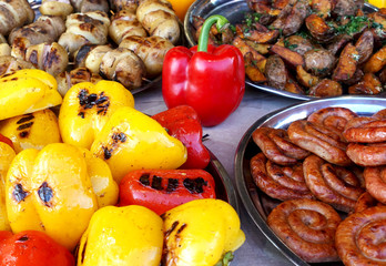 Grilled pepper, fried sausages and other vegetables on plates. Street food close-up