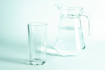 Pure clear water in a glass and jug stands on a white background