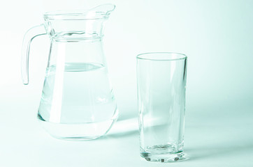 Pure clear water in a glass and jug stands on a white background