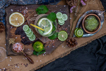Cold water with lemon, kaffir lime, cucumber and mint leave on wooden background.