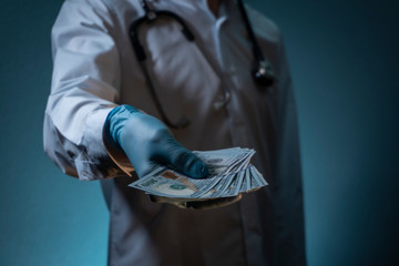 Doctor in a clinic holds a pack of dollars