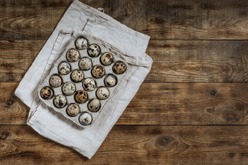 On a wooden table quail eggs in a box
