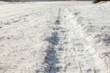 Track from a wheel on an icy track. Dangerous driving conditions. Icy road with tracks from the wheels of cars. The concept of safe driving on a winter slippery track.