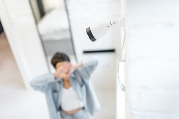 Woman spotted by a video camera mounted on the wall indoors. Concept of a home video surveillance