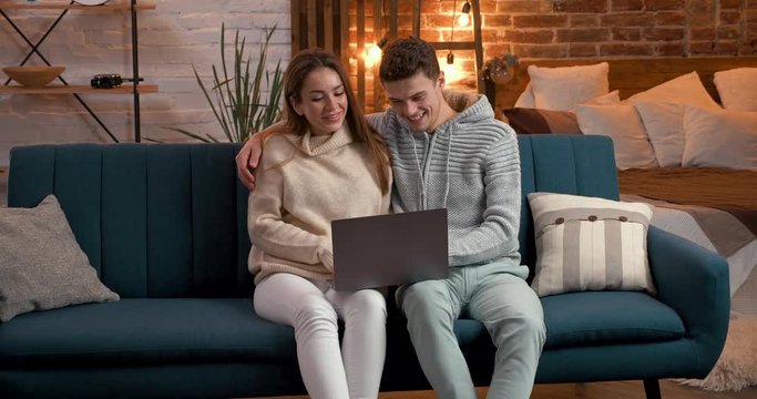 Young Couple making Video-Call at new modern Flat-Studio, Loft Interieur. Young Family speaks on Skype with Relatives, sharing good Emotions. Mood: Family, Home, Young Couple. Perfect Relations.
