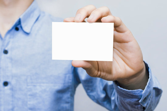 Man holding white business card on concrete wall background,mockup template,Business man blue shirt