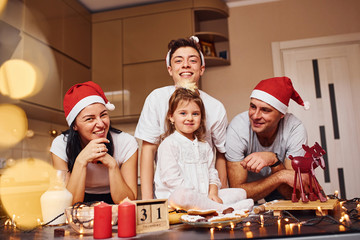 Festive family in christmas hats have fun on the kitchen and preparing food