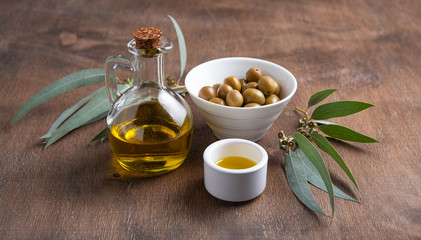 ripe natural eco friendly olives with olive oil in a bottle on a brown wooden background.