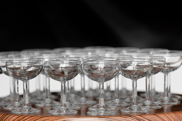 Many elegant empty glasses of wine or champagne on the wooden table in wedding day. Set of blank empty glasses displayed in rows. Preparation for the holiday