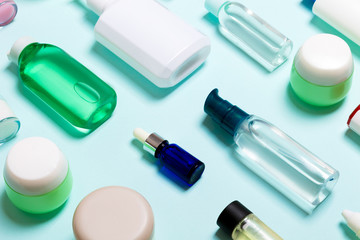 Top view of cosmetic products in different jars and bottles on blue background. Close-up of containers with copy space