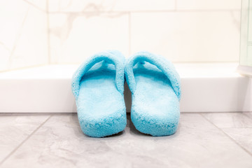 Soft comfortable blue thong slippers in a bright clean bath scene. 