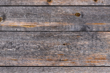 Outdoor wooden flooring from the planks. Knots, scratches and black lines between the boards. Texture for background.