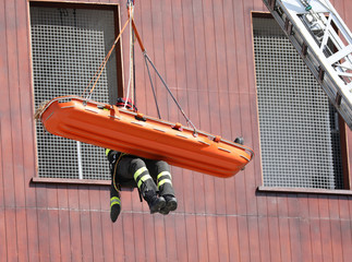 suspended firefighter with stretcher with people during practice