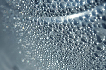 Drops of water close-up. The texture of the drops. Drops on the surface of a plastic bottle. Drawing of a drop of different sizes. Abstract blue background made of drops