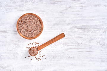  Psyllium Husk seeds , fiber source , in wooden bowl on white wooden background. Top view with copy space  