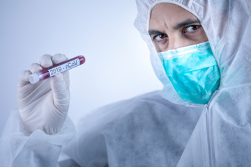 medico con tuta protettiva e mascherina tiene in mano una provetta per il test del sangue del...