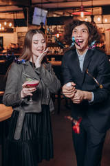 young girl in black dresses and a curly haired guy have fun in a restaurant